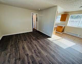 A room with wood flooring and a doorway leading to another room.