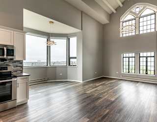 an empty living room with a kitchen and a large window