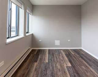 an empty room with wood flooring and a window