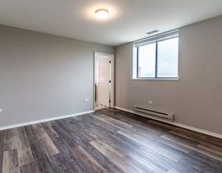 an empty living room with wood flooring and a window