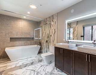 a bathroom with a tub and two sinks and a mirror