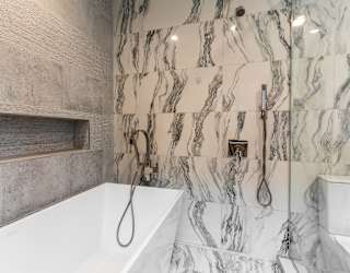 a marble bathroom with a tub and shower and a sink