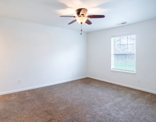 an empty room with a ceiling fan and a window