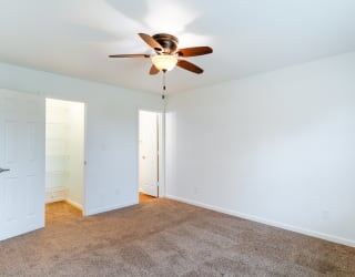 a living room with a ceiling fan and a carpet
