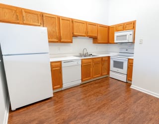 an empty kitchen with white appliances and wooden cabinets