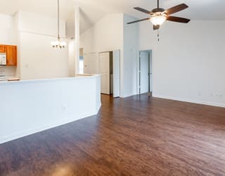 an empty living room with wood flooring and a ceiling fan