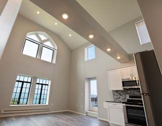 a kitchen and living room with high ceilings and windows