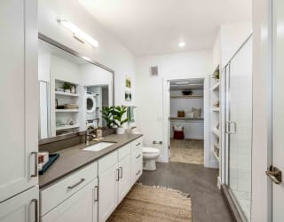 a bathroom with white cabinets and a shower and a sink