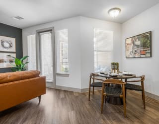 a dining area with a wooden table and chairs and a leather couch