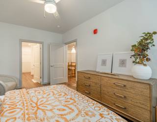 A bedroom with a bed, dresser, and two doors.
