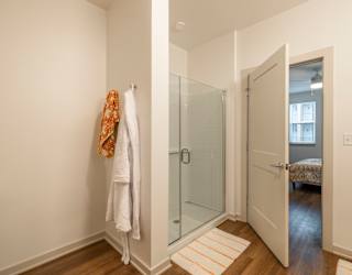A white towel is hanging on a white wall next to a glass door.
