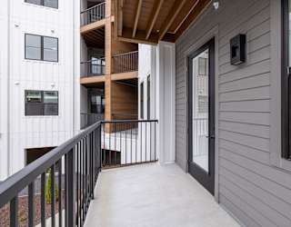 A balcony with a black railing and a grey wall.