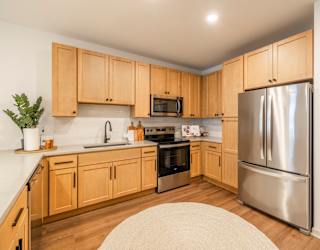 A kitchen with wooden cabinets and a stainless steel refrigerator.