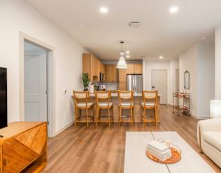 A modern living room with a dining area and a kitchen in the background.