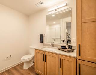 A bathroom with a toilet, sink, and mirror.