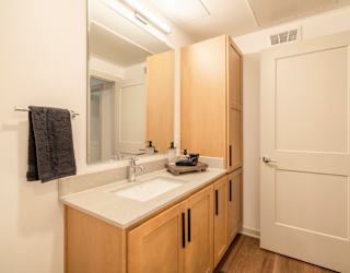A bathroom with a sink, mirror, and wooden cabinets.