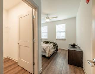 A bedroom with a bed, nightstand, and a window with blinds.