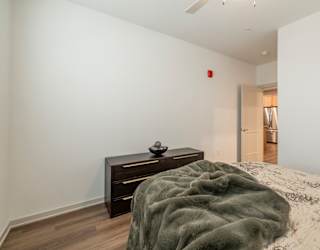 A bedroom with a bed, a nightstand and a door.