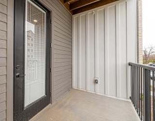 A balcony with a glass door and a black railing.