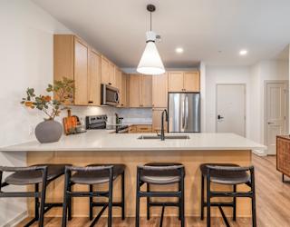 A kitchen with a white countertop and bar stools.