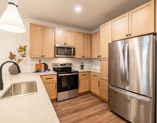 A kitchen with a stainless steel refrigerator and wooden cabinets.