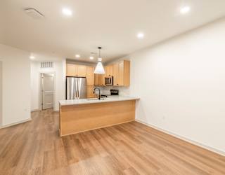 A kitchen with wooden floors and a white wall.
