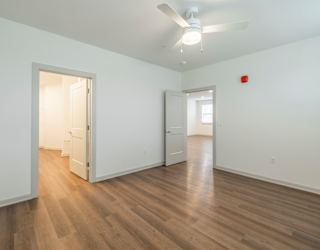 A room with a ceiling fan and wooden flooring.
