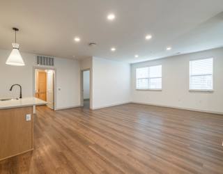 A large empty room with wooden floors and white walls.