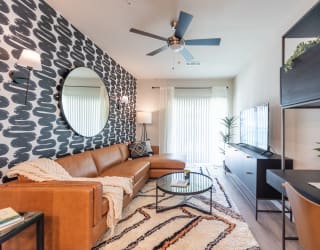 a living room with a brown couch and a black and white accent wall