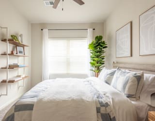a bedroom with white walls and a white bed with a blue and white comforter