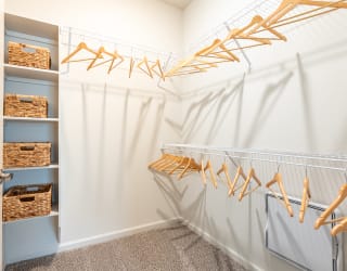 a walk in closet with white walls and a white closet door with gold hangers