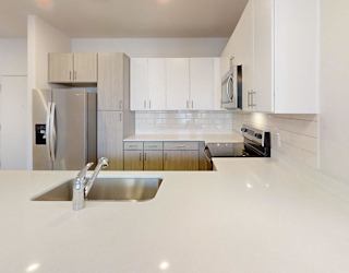 A modern kitchen with white cabinets and a stainless steel refrigerator.