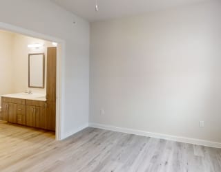 a bedroom with white walls and wood floors and a bathroom