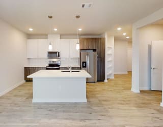 a white kitchen with a large island and a stainless steel refrigerator