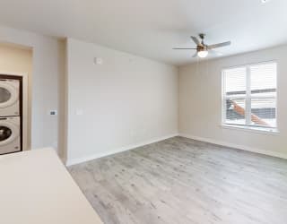 an empty living room with a ceiling fan and a window