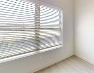A room with a window covered by white blinds.