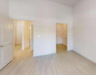 A white room with a wooden floor and a door on the left.