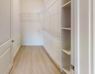 A white pantry with a white door and white shelves.