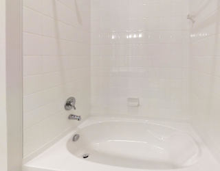 A white bathtub in a bathroom with a white tile wall.