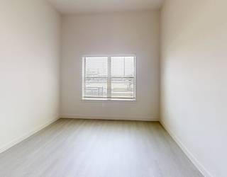 A room with a window covered by white blinds.