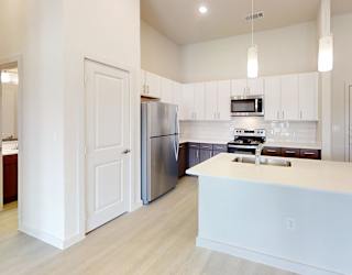 A kitchen with white cabinets and a white island.