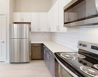 A modern kitchen with a stainless steel refrigerator and a stove top oven.