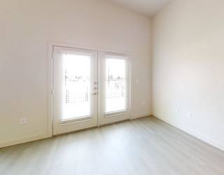 A room with a white wall and a window with blinds.