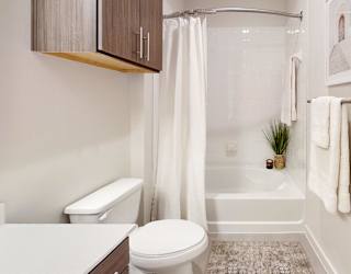 A white toilet sits next to a white bathtub in a bathroom.