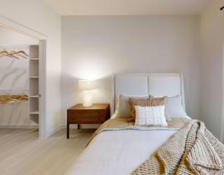 A bedroom with a bed, nightstand, and window with blinds.