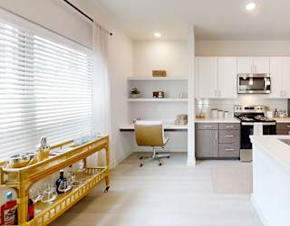 A modern kitchen with a white countertop and a wooden rolling cart.