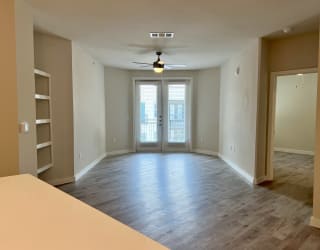 an empty living room with a ceiling fan and bookshelf