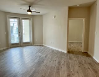 an empty living room with a ceiling fan and french doors