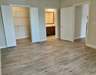 a bedroom with hardwood floors and a doorway leading to a bathroom