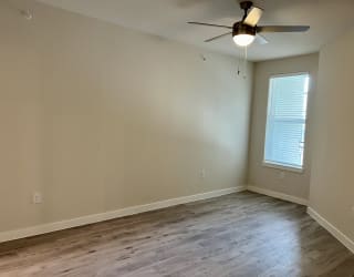 an empty room with a ceiling fan and a window